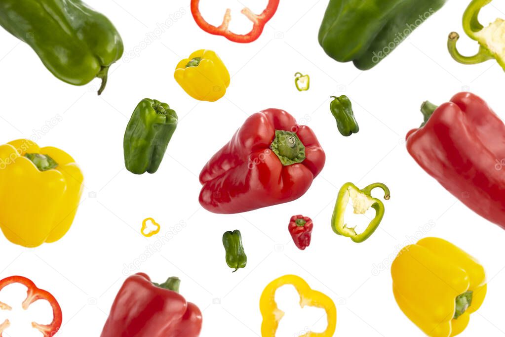 Healthy red, green and yellow peppers flying through the air isolated on white background. Concept of healthy food, lifestyle and wellness. Creative pattern.