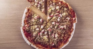 Farklı insanların ellerini görebildiğiniz, taşralı ahşap bir tabakta lezzetli bir ton balıklı pizzayı dilimleyen videoları durdurun..