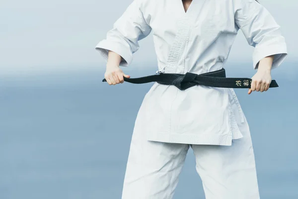 Unknown female karate athlete lacing black belt on her waist