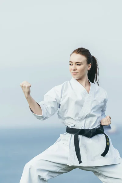 Redhead female karate athlete preparing to attack with punch