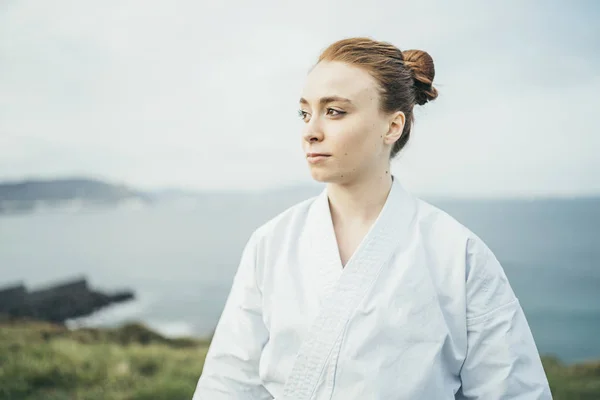 Young female karate athlete looking away on top of a cliff