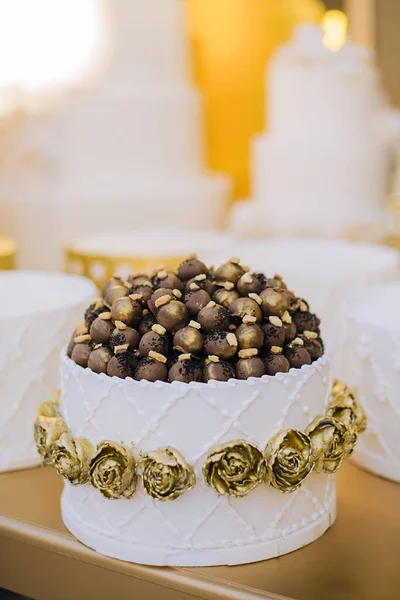 Wedding sets of sweets laid out in the shape of a pyramid, decorated with edible gold. Milk chocolate candies in the form of balls, flowers.