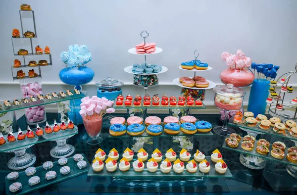 Marshmllou on wooden sticks at a festive catering in honor of the holiday where parents will recognize the gender of the child Baby Shower. On the table are various sweets and snacks.