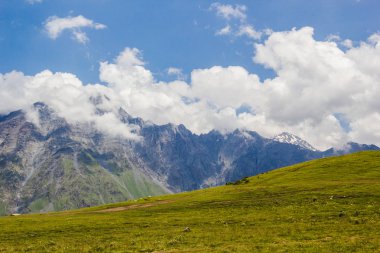 Kazbeki bölgede bulutlu mavi gökyüzü ile kayalık Kafkas Dağları 