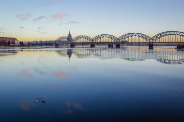 Demiryolu Köprüsü donmuş nehir üzerinde karlı kış Riga sırasında güneş