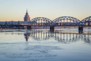 Demiryolu Köprüsü donmuş nehir üzerinde karlı kış Riga sırasında güneş
