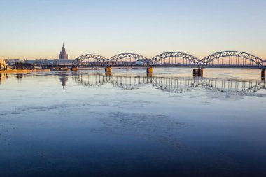 Demiryolu Köprüsü donmuş nehir üzerinde karlı kış Riga sırasında güneş