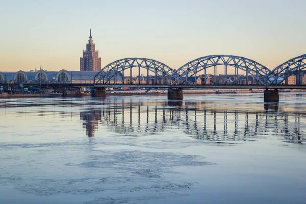 Demiryolu Köprüsü donmuş nehir üzerinde karlı kış Riga sırasında güneş