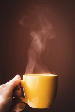 Sarı fincanda sıcak çay ellerinde.
