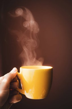 Sarı fincanda sıcak çay ellerinde.