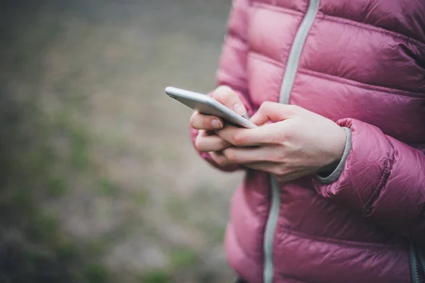 Manos en jaket rosa sosteniendo mientras el teléfono móvil — Foto de Stock