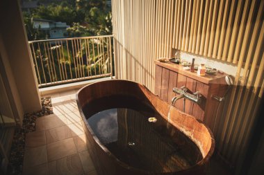 Brown wooden bath tub full with water on the balcony with picturesque view on green jungles forest of palm trees in Ao Nang village in Krabi province, Thailand clipart