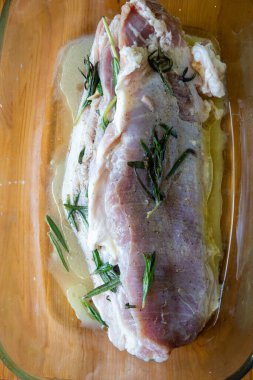 Tuz, kağıt, sarımsak ve biberiye dallarıyla tatlandırılmış çiğ domuz eti.