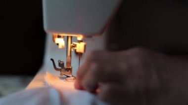 Beyaz dikiş makinesi ve iğneli renkli iplikler.