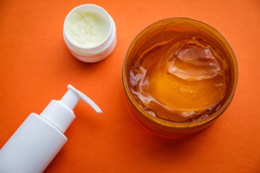 Güzellik ürünleri parlak turuncu arka planda, saç bakımında ve yüz bakımında, salyangoz losyonunda, serumda, ahşap tarakta ve kaplıcada boş kopya spa detaylarında yatıyordu.