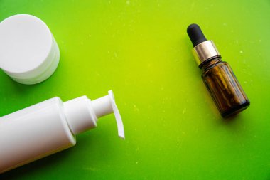 Güzellik ürünleri düz parlak yeşil arka plan, saç bakımı ve yüz bakımı öğeleri, losyon ve boş beyaz ambalaj kopya spave serumu üzerine yatıyordu