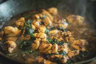 Tayland fesleğeni kızartma tavasında kontrol ediliyor, geleneksel kızartılmış yemek pişiriliyor, yeşil fesleğen yaprağıyla doğranmış tavuk pirzolası kızartılıyor.