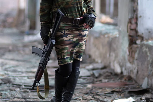 Chica en uniforme militar con un arma de fuego en un edificio abandonado. Chica en ropa de camuflaje verde con una ametralladora rusa . — Foto de Stock