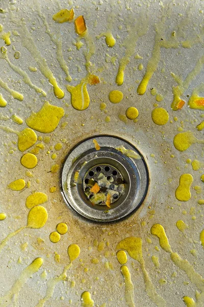 A dirty and littered sink with yellow grease stains.