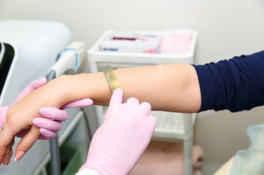 Genç bir kadın lazer epilasyon için hazırlanıyor. Mavi elbise ve gözlük bir kız bir lazer ile saç kaldırmak için salonda.