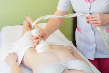 Kaviteli vücut masajı. Masaj masasındaki genç kız selülit masajı karşıtı.