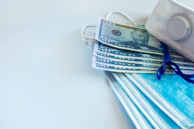 Tıbbi maskeler ve 50 dolarlık banknotlar, solunum yolunu virüslerden korumak için artan fiyatların sembolü. Kopyalama için bir yer var.