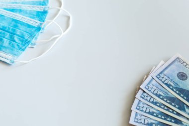 Tıbbi maskeler ve 50 dolarlık banknotlar, solunum yolunu virüslerden korumak için artan fiyatların sembolü. Kopyalama için bir yer var.