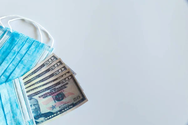 Tıbbi maskeler ve 50 dolarlık banknotlar, solunum yolunu virüslerden korumak için artan fiyatların sembolü. Kopyalama için bir yer var.