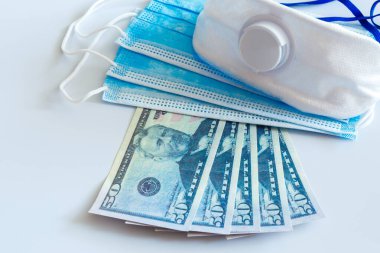Tıbbi maskeler ve 50 dolarlık banknotlar, solunum yolunu virüslerden korumak için artan fiyatların sembolü. Kopyalama için bir yer var.
