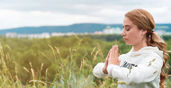 Şehir dışında meditasyon, doğada. Genç bir kadın yerde oturmuş meditasyon yapıyor. Kopya yapıştırıcısı için bir yer var.