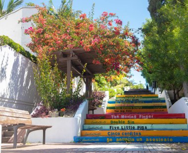 Üzerinde Agatha Christies 'in kitap başlıkları yazan çok renkli merdivenler. Coronavirus salgını sırasında Puerto de la Cruz 'un sokak manzarası. Puerto De La Cruz, Kanarya Adaları, İspanya