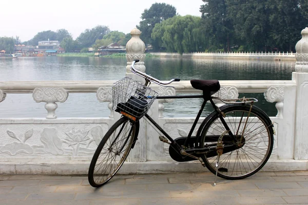 La vecchia bicicletta inutilizzata giaceva sulla ringhiera del parco del lago houhai, Pechino — Foto Stock