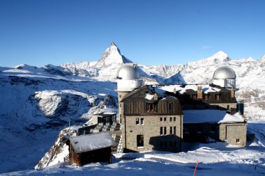 Mavi gökyüzü ile güneşli günde karlı Matterhorn tepe ve arka planda bazı bulutlar doğal görünümü