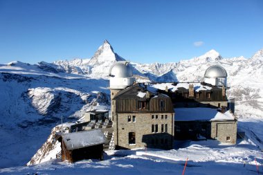 Mavi gökyüzü ile güneşli günde karlı Matterhorn tepe ve arka planda bazı bulutlar doğal görünümü