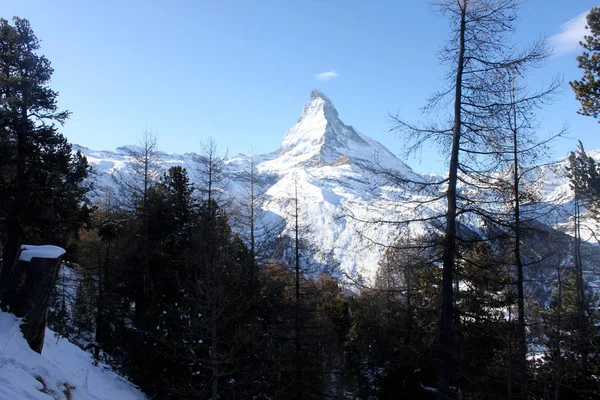 Scenic view on snowy Matterhorn peak in sunny day with blue sky and some clouds in background — Stock Photo, Image