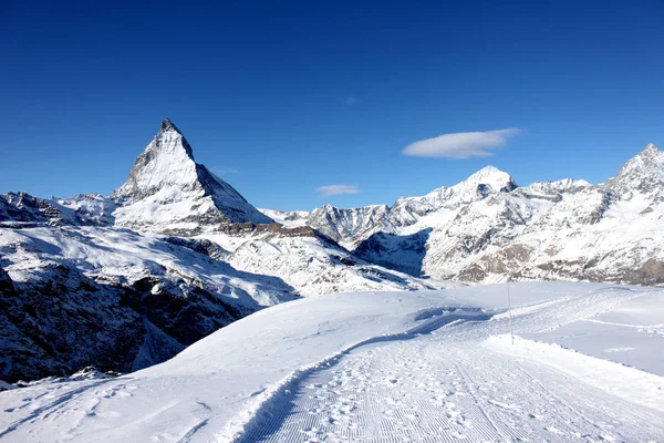 Vista panoramica sulla vetta innevata del Cervino nella giornata di sole con cielo blu e alcune nuvole sullo sfondo — Foto Stock