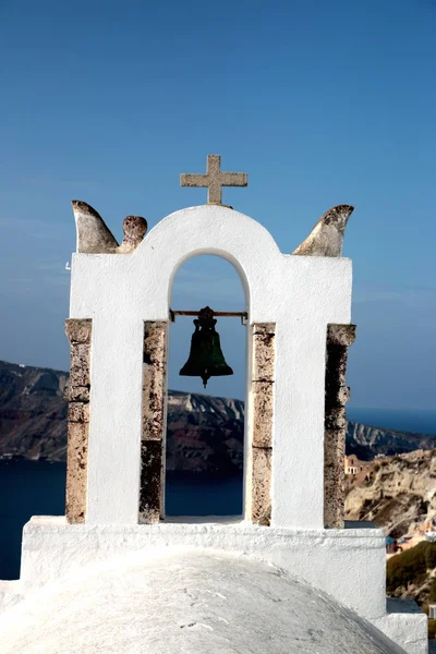 View of sea surface through traditional Greek white church arch with cross and bells in Oia village of Cyclades Island, Santorini, Greece Stock Image
