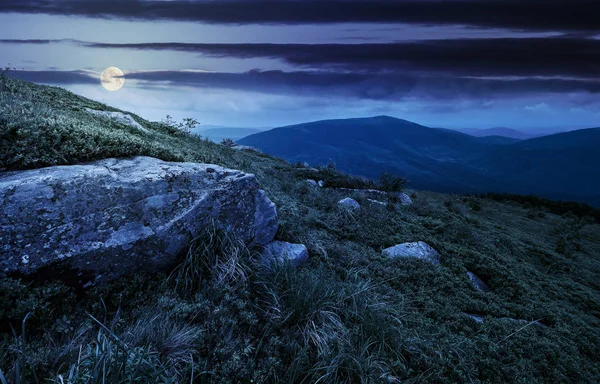 在夜间长满草的山坡上的巨石 — 图库照片