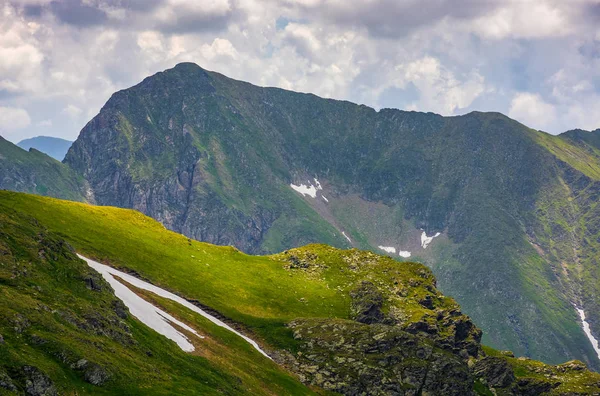 Kar ile çimenli yamaca kayalık kenar — Stok fotoğraf