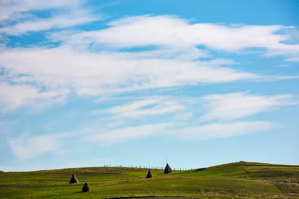 Сіно стоїть на схилі пагорбів під прекрасним небом — стокове фото