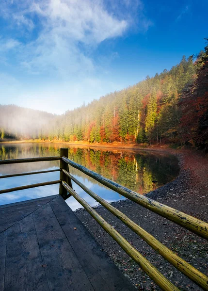 Cerca de madera perforada en un lago en la niebla — Foto de Stock
