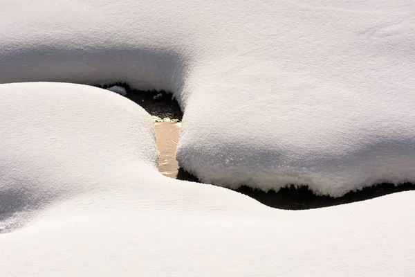 Ozdobný sníh rozložení na břehu potoka — Stock fotografie