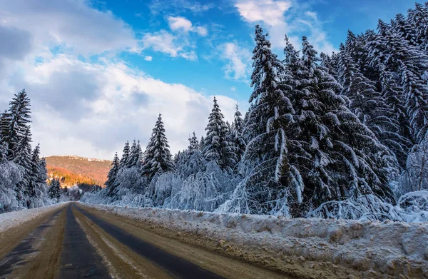 Snowy road through mountains in evening — Stock Photo, Image