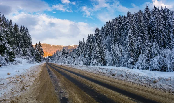 Besneeuwde weg door bergen in avond — Stockfoto