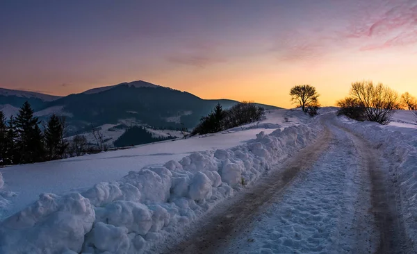 Kırsal yol yokuş yukarı gün batımında karda — Stok fotoğraf