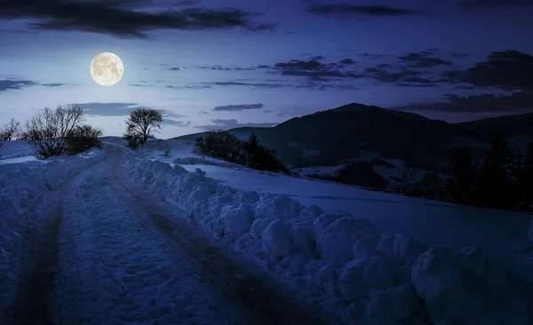 Venkovské cestě do kopce ve sněhu v noci — Stock fotografie