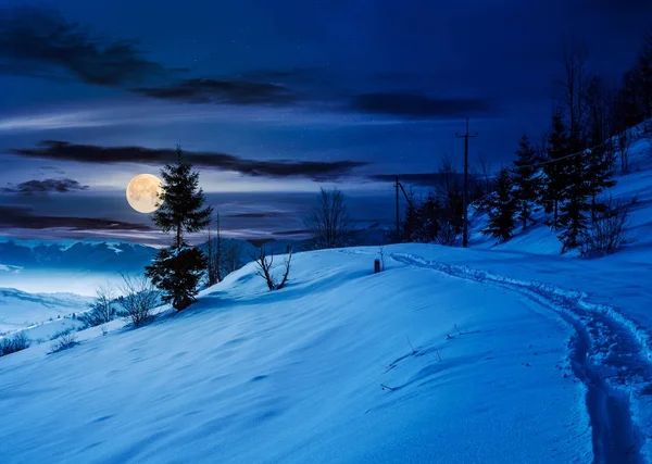 Caminho rural através de encosta nevada à noite — Fotografia de Stock