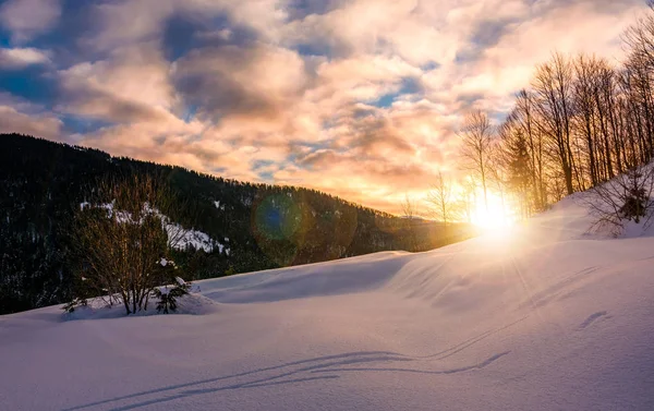 Sol nascendo atrás da encosta nevada — Fotografia de Stock