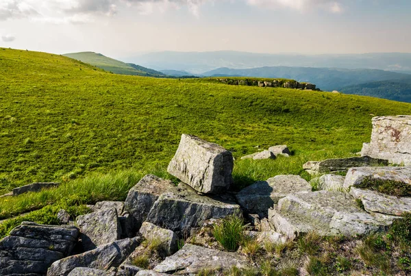 Stenar på gräsbevuxen äng på toppen av en kulle — Stockfoto