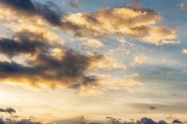 Gün batımında mavi gökyüzünde altın bulutlar